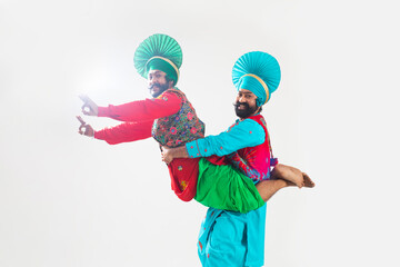 Wall Mural - Two Bhangra dancers striking a classic step of their dance form.	