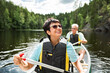 © Suzi Media  - Happy mature couple in life vests canoeing in forest lake. Sunny summer day. Tourists traveling in Finland, having adventure.
