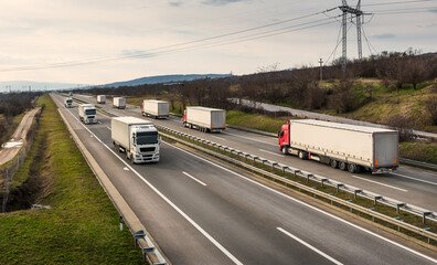 Wall Mural - Convoys or caravans of transportation trucks passing on a highway on a bright blue day. Highway transportation with white and red lorry trucks