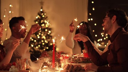 Sticker - holidays, celebration and people concept - happy friends with sparklers having christmas dinner at home