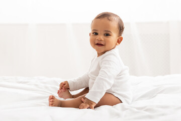 beautiful african baby boy sitting in bed posing in bedroom