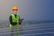 © SimpleBen.CNX - An engineer works on the inspection and maintenance of equipment at roof-mounted solar power plants of condominium buildings, houses with a tabletop in his hand.