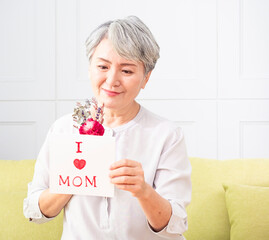 Wall Mural - Senior Asian woman receives greeting card and flowers in mother's day.