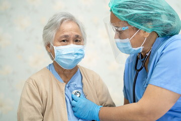 Doctor using stethoscope to checking Asian senior or elderly old lady woman patient wearing a face mask in hospital for protect infection Covid-19 Coronavirus.