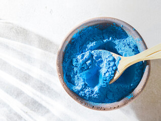 Blue Spirulina algae powder on gray concrete background. Concept dieting, detox, healthy superfood, which contains protein.