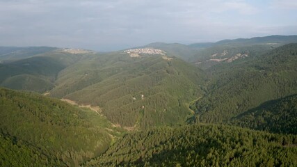 Wall Mural - drone flight over green mountain slopes and a small villages nestled in them, the rhodopes in bulgar