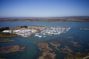 Wall Mural - Northney Marina with moored yachts and boats on the pontoons situated on shore of Hayling Island in the beautiful Langstone Harbour., aerial view.