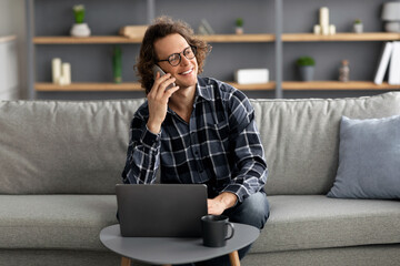 Poster - Cheerful Man Talking On Cellphone Sitting With Laptop At Home
