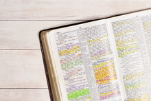 Used And Highlighted Bible Open On A White Wood Table