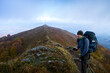 © vzwer - A tourist with a large backpack and a mobile phone. Tourist in the mountains during the fog.