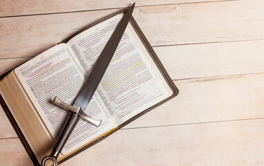 Sticker - Bible with a Sword on a Bright White Wooden Table