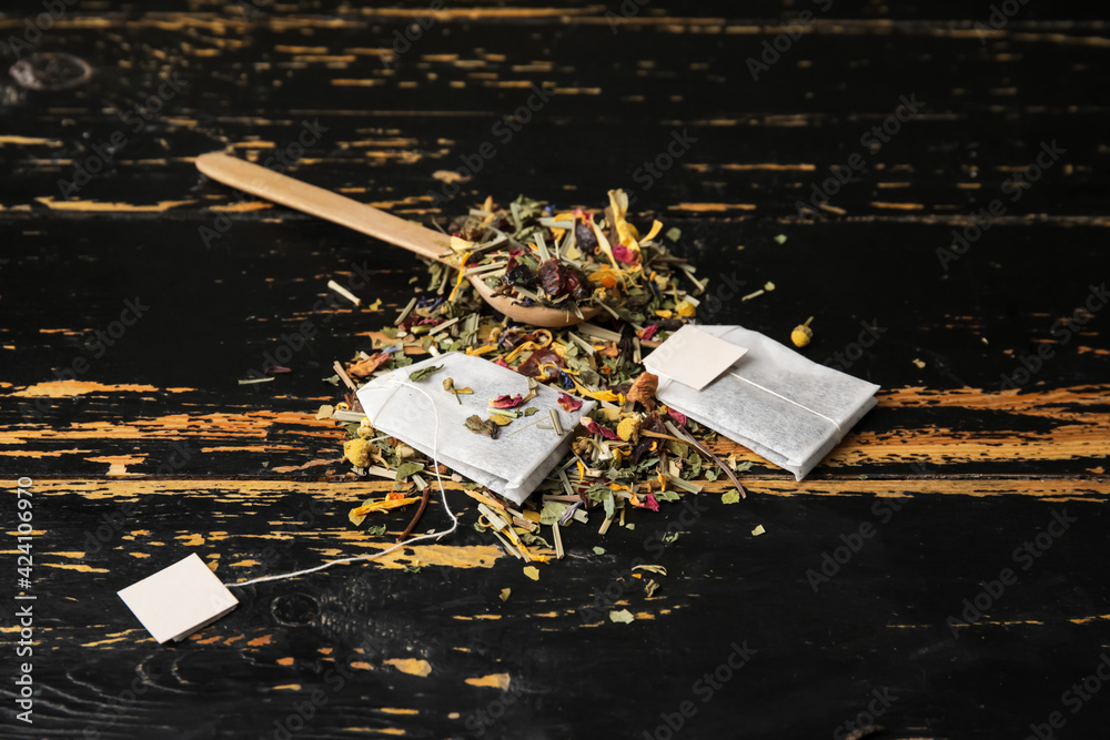Tea bags and dry herbs on dark wooden background
