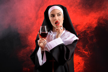 Wall Mural - Naughty nun with glass of wine on dark background