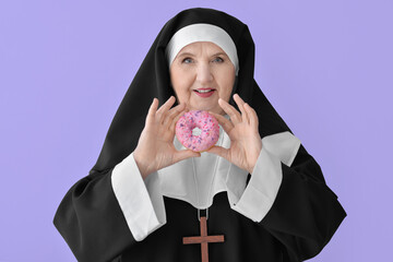 Senior nun with donut on color background