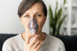 Headshot of sick senior lady using oxygen mask at home, a mature woman has labored breathing, treatment at home