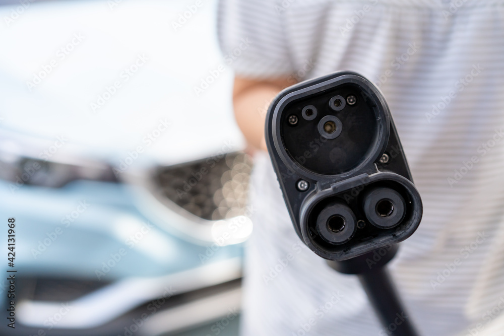 Unrecognizable Asian woman holding aa DC - CCS type 2 EV charging ...