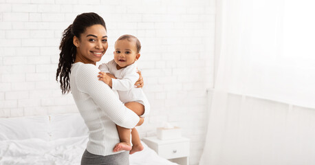 young black mom holding baby toddler posing standing indoors, panorama