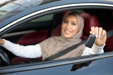 Wall Mural - Muslim woman showing auto key, sitting on driver's seat