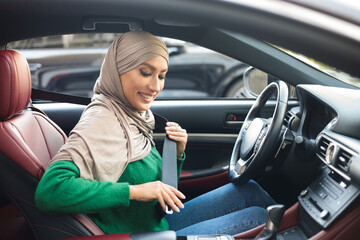 Wall Mural - Smiling Muslim Woman In Hijab Putting On Seat Belt