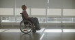 © nimito - Mature woman in wheelchair riding across hospital corridor