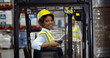 © TommyStockProject - Female african forklift driver working in warehouse