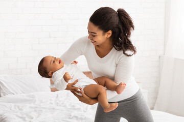 Wall Mural - African Mother Holding Baby Playing With Toddler In Bedroom Indoors