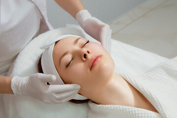 A young woman with perfect skin gets a facial massage at a cosmetology clinic