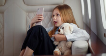 Adorable Little Girl With Teddy Bear Talking On Video Chat On Smartphone Traveling By Airplane.
