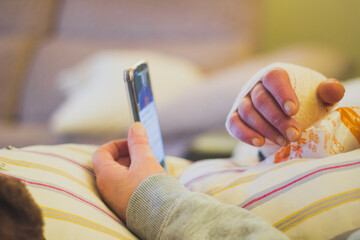 bandaged woman's hand resting on a cushion, woman watching the mobile