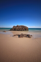 Sticker - Beach with turquoise sea water with rocks. Long exposure