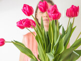 Fototapeta Tulipany - Faceless concept. Beautiful young woman with tulip bouquet. Spring portrait. Bright pink flowers in girl's hands.
