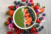 Matcha Green Tea Breakfast Superfoods Smoothies Bowl Topped With Strawberries, Blueberries, Coconut Flakes Overhead, Top View, Flat Lay