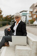 © Johnér - Senior woman using laptop on stairs