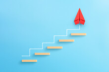 Wooden Block Stacking As Step Stair With Red Paper Plane On Blue Background, Ladder Of Success In Business Growth Concept, Copy Space