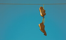 Old Sneakers Hanging On Cable Wire Against The Sky