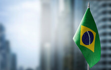 A Small Flag Of Brazil On The Background Of A Blurred Background