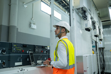 Poster - Electrical engineer working on the tablet and recording the voltage current and power of electrical power distribution board in switch gear room