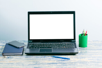 Wall Mural - Workplace with mockup letterhead on laptop screen, smartphone, notepad and pens on table