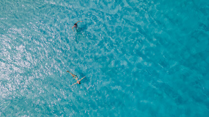 Wall Mural - Couple of woman floating in clear blue ocean. Aerial view