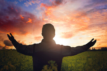 Wall Mural - Easter concept: man raising his hands in worship on sunset background