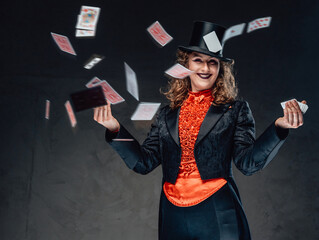 Female artist in black clothes shuffles poker cards in studio