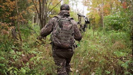bow hunter walking through forest the with hunting gear.