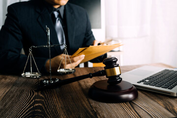 Justice and law concept.Male judge in a courtroom with the gavel, working with, computer and docking keyboard, eyeglasses, on table in morning light