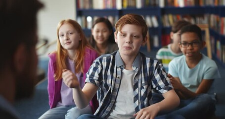 Poster - Redhead boy raising hand during lesson in school library