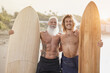 Happy father and adult son on the beach with surfboard - Surfer men having fun outdoor
