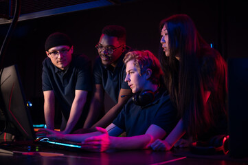 Wall Mural - Two guys and a girl in medical masks in a computer club give support to their friend during his game