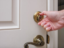 Close Up Of Man Locking Deadbolt Door Lock On White Entry Door. Home Security Burglar And Robbery Prevention.