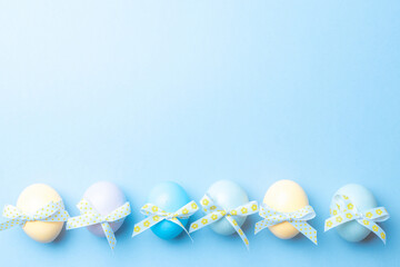 Wall Mural - Easter eggs background. Colourful egg with tape ribbon on pastel blue background in Happy Easter decoration. Foil minimalist egg design, modern top view template.