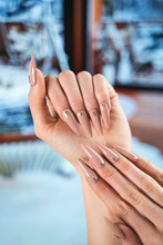 Luxury Manicure Sculpted Nude Gel Nails With Swarovski Crystals On Beautiful Women's Hands Against A Cool Winter Cabin Background