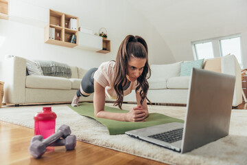 Wall Mural - Woman training at home in a plank position